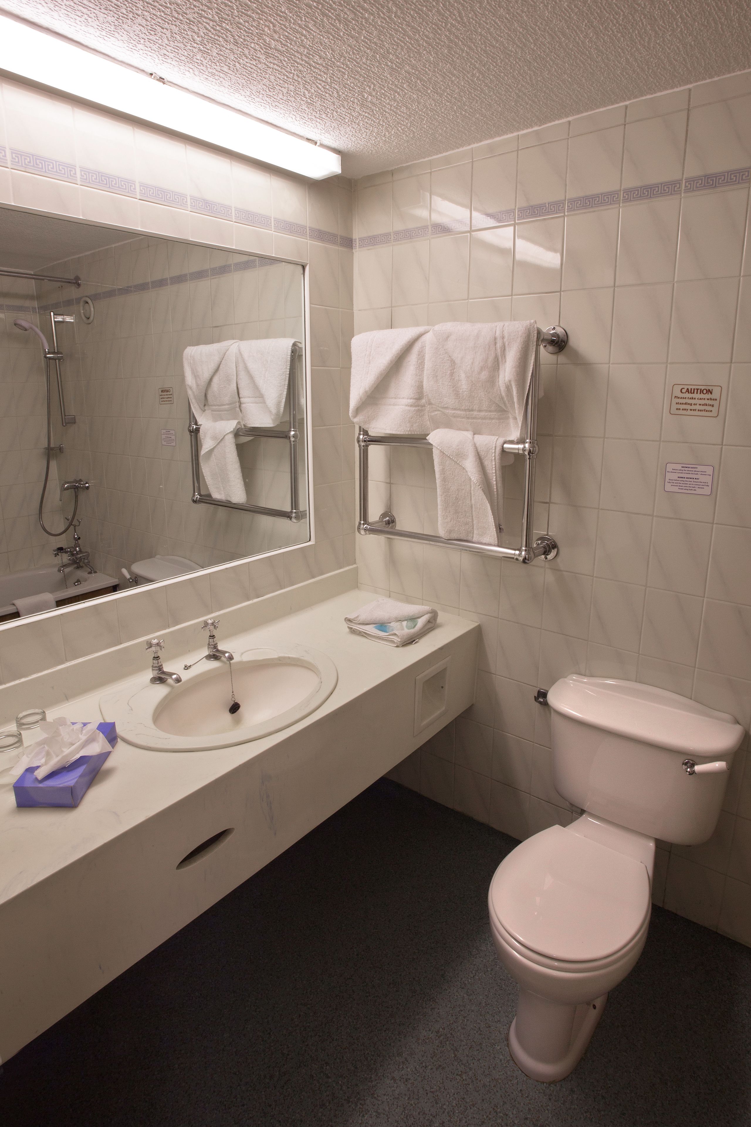 Un baño con lavamanos, espejo, toallero y retrete.