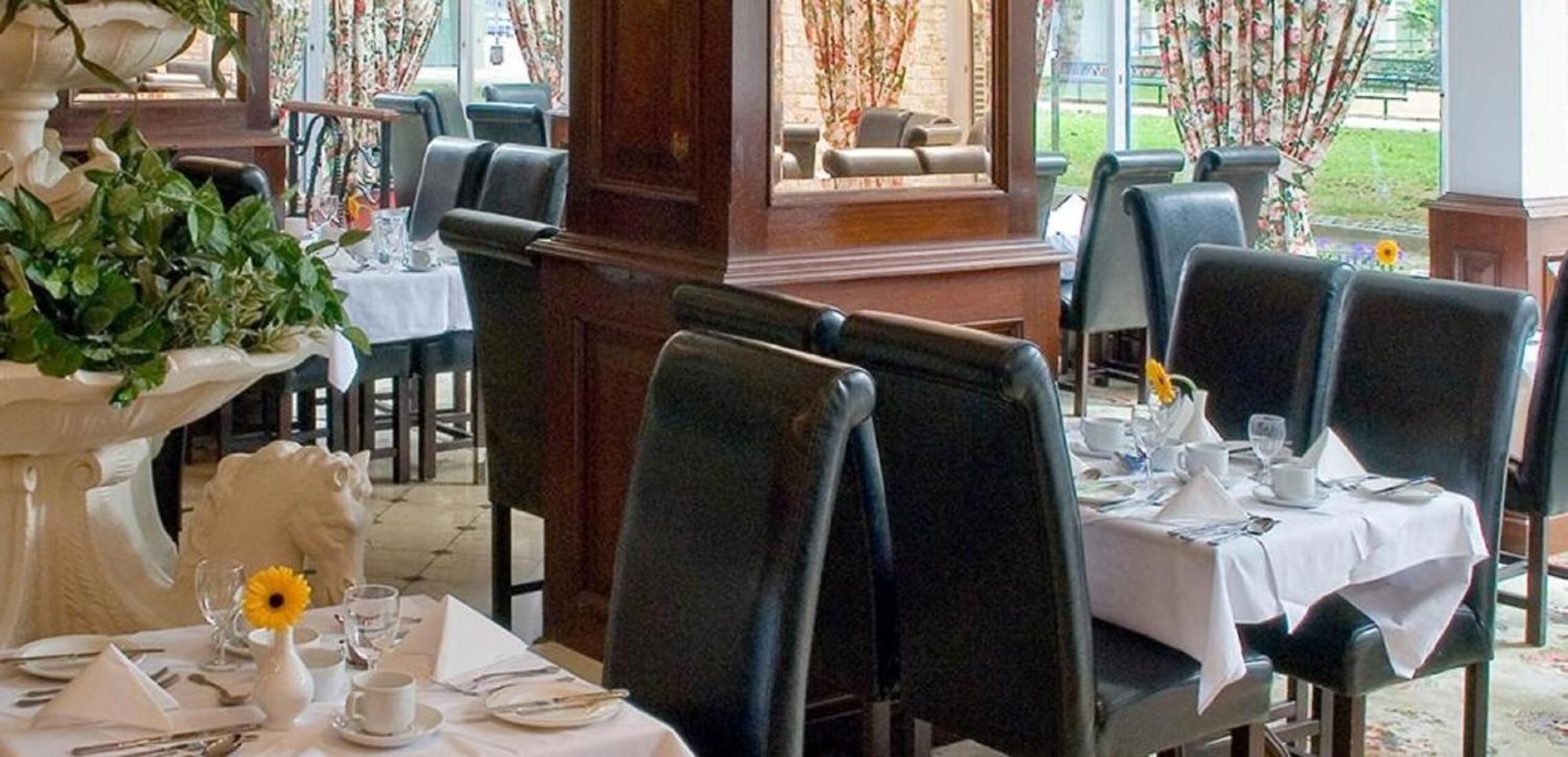 Un restaurante con mesas dispuestas para comer, sillas y una fuente decorativa.