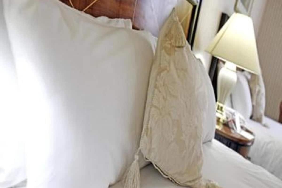 A neatly made bed with white linens and a decorative pillow.