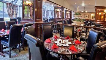A restaurant with round tables set for dining, surrounded by leather chairs.