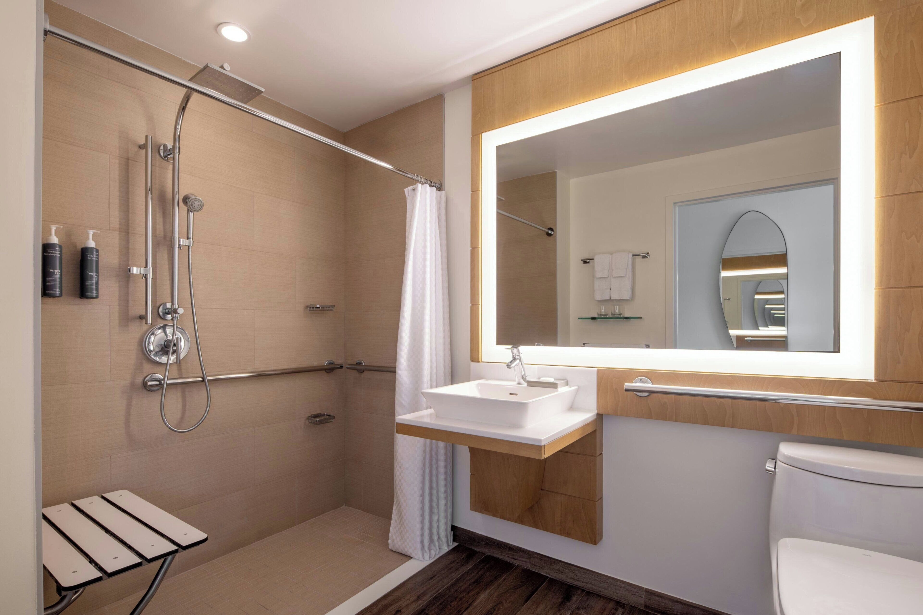 A modern bathroom with a walk-in shower, a vanity with a mirror, and a toilet.