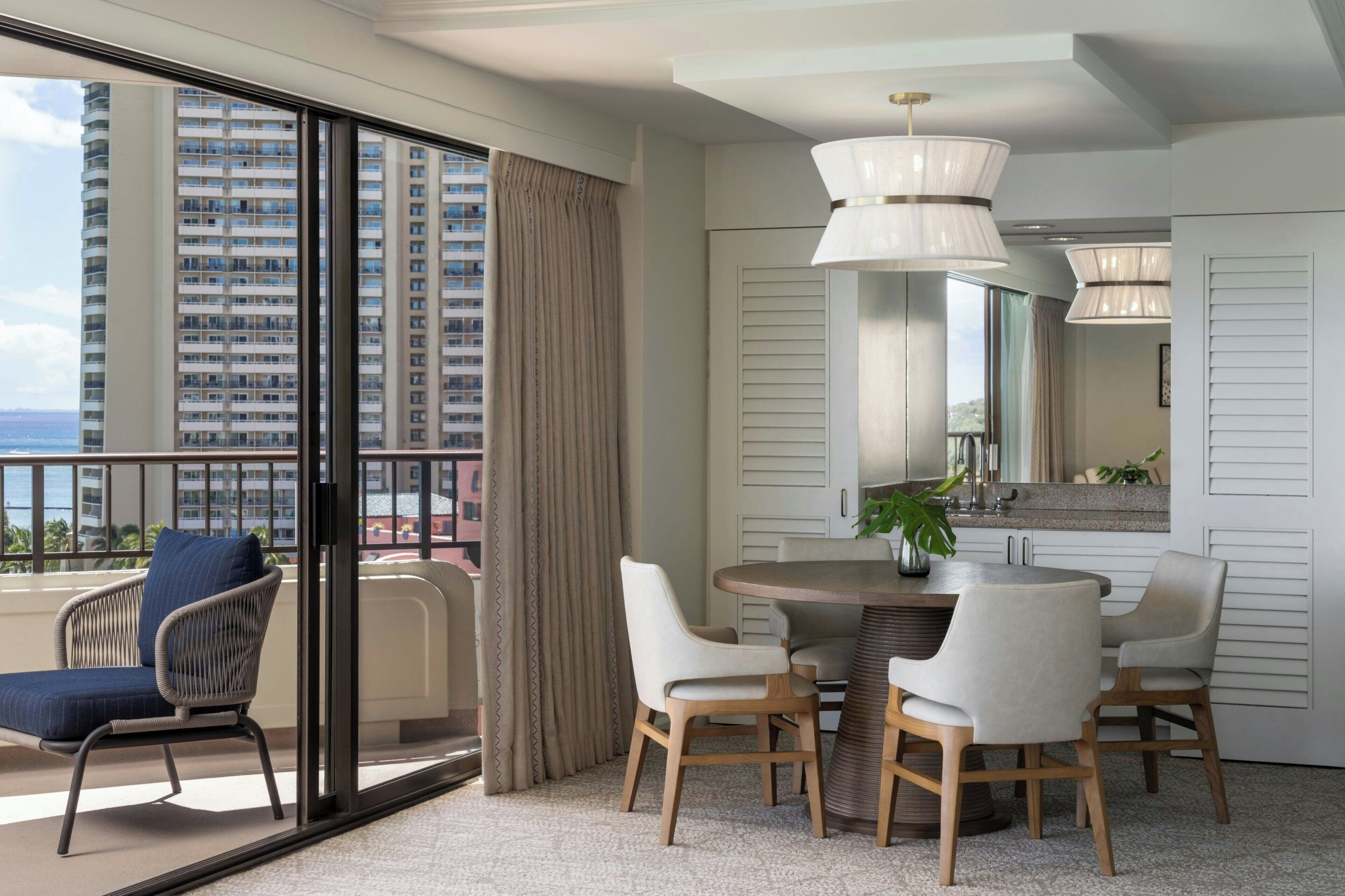 Une chambre d’hôtel moderne dotée d’un balcon, d’un coin repas avec une table ronde et des chaises, et d’une grande fenêtre avec des rideaux.