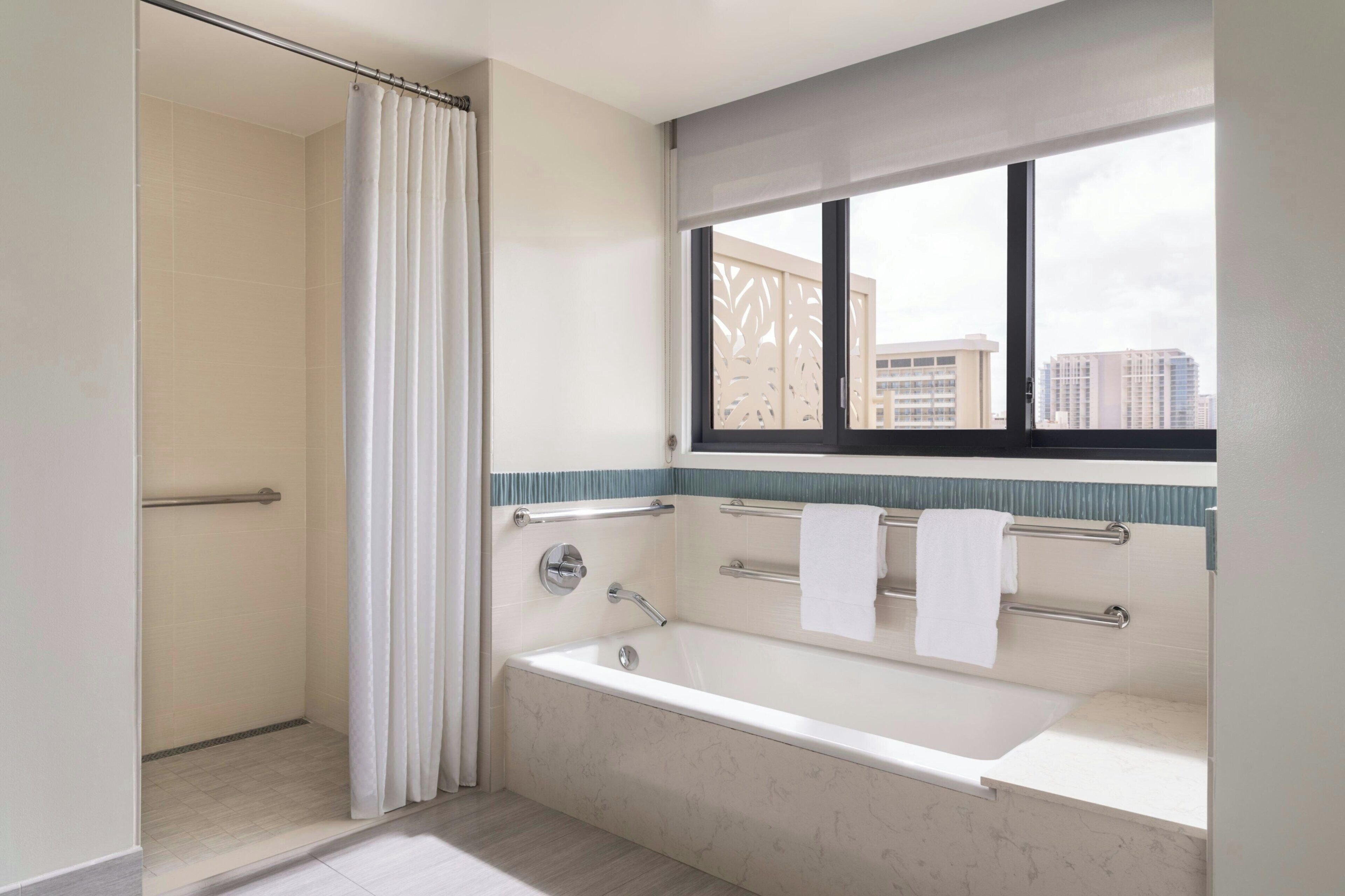 A modern bathroom with a bathtub, shower, and window.