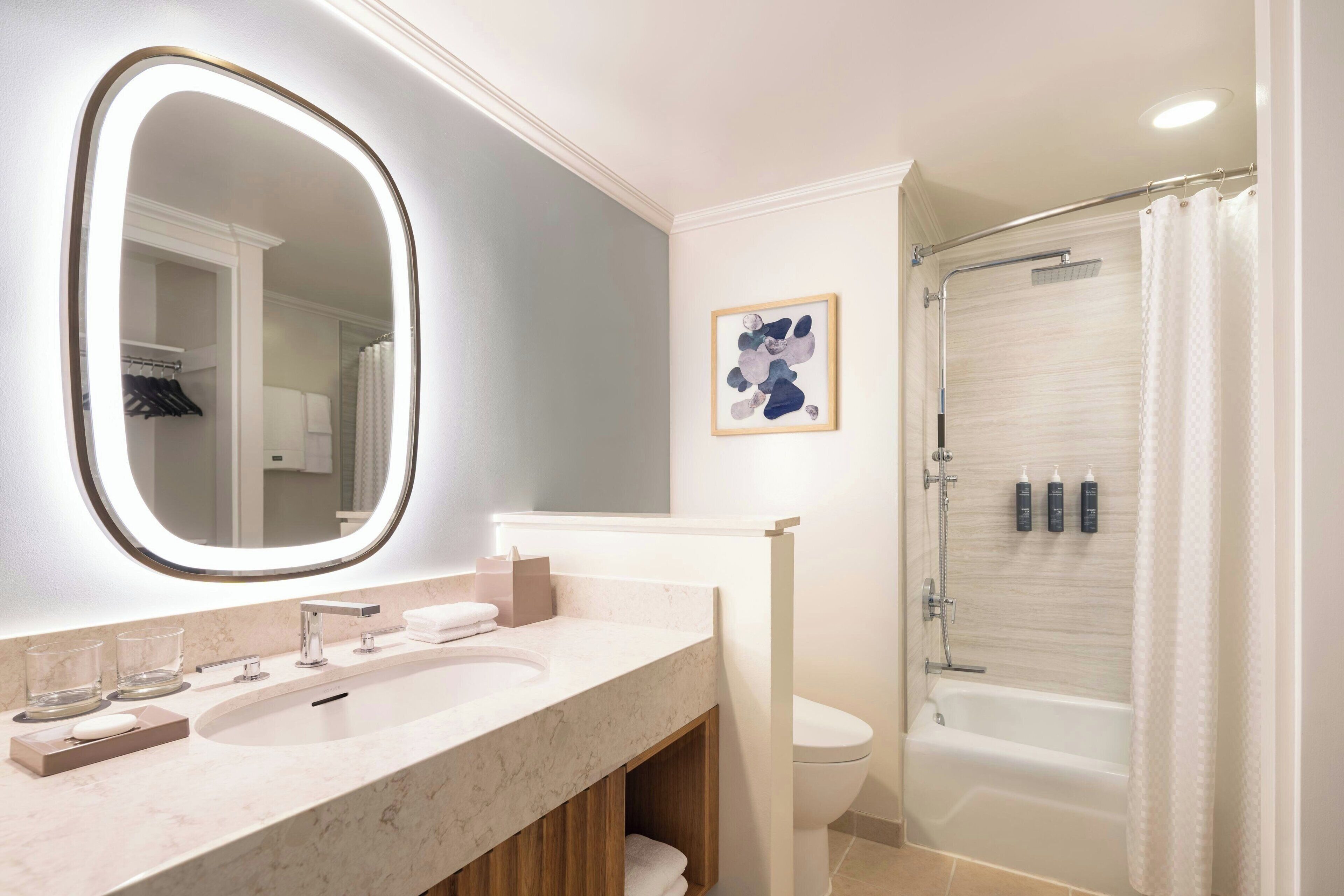 Un baño moderno con un espejo grande, dos lavamanos, un inodoro y ducha con mampara de cristal.