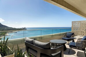 A balcony with outdoor furniture, a glass railing, and a view of the ocean and coastline. - Moana Surfrider, A Westin Resort & Spa, Waikiki Beach (Honolulu)