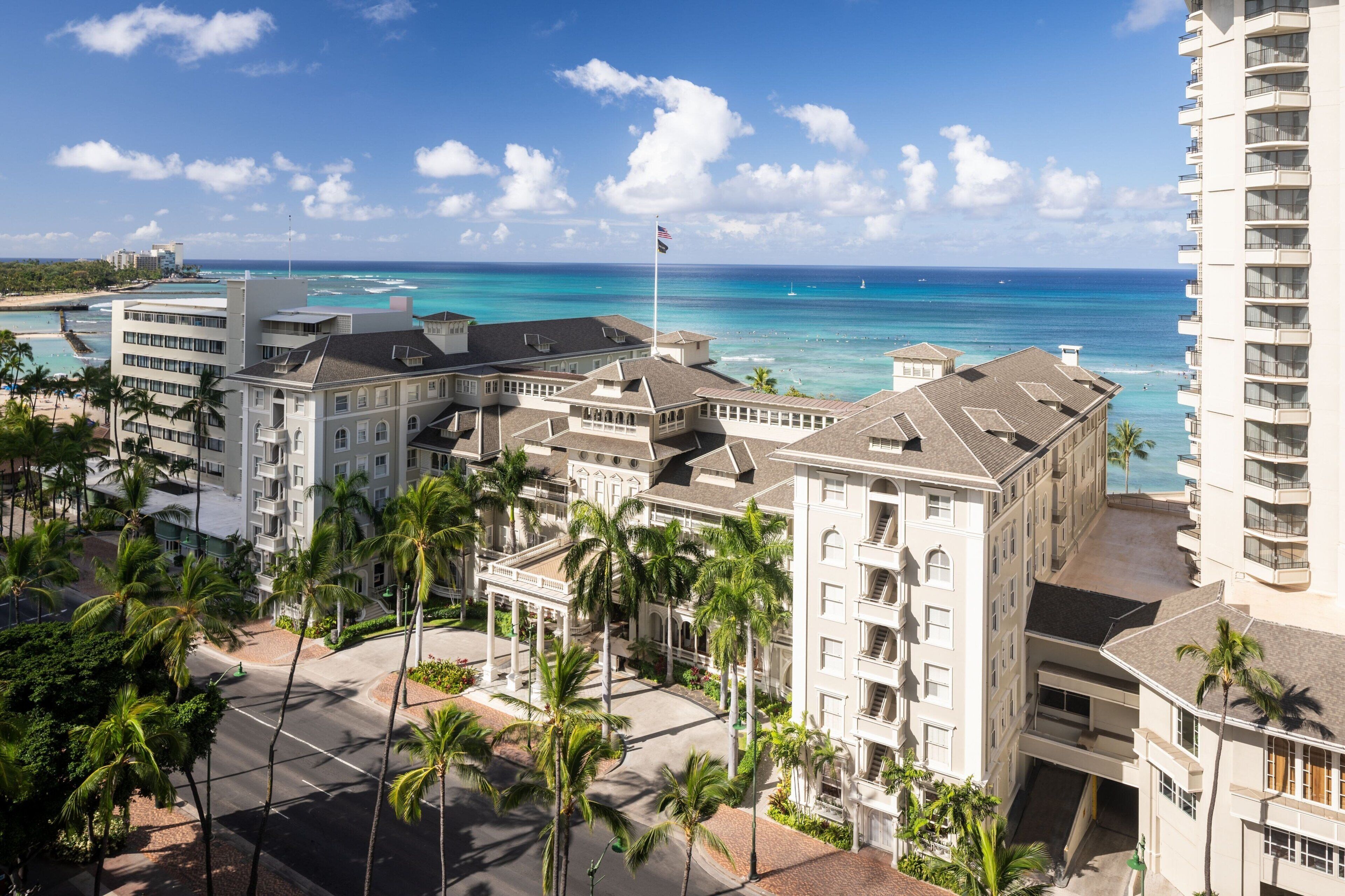 Un hôtel à étages, doté d’une cour intérieure agrémentée de palmiers et offrant une vue sur l’océan.
