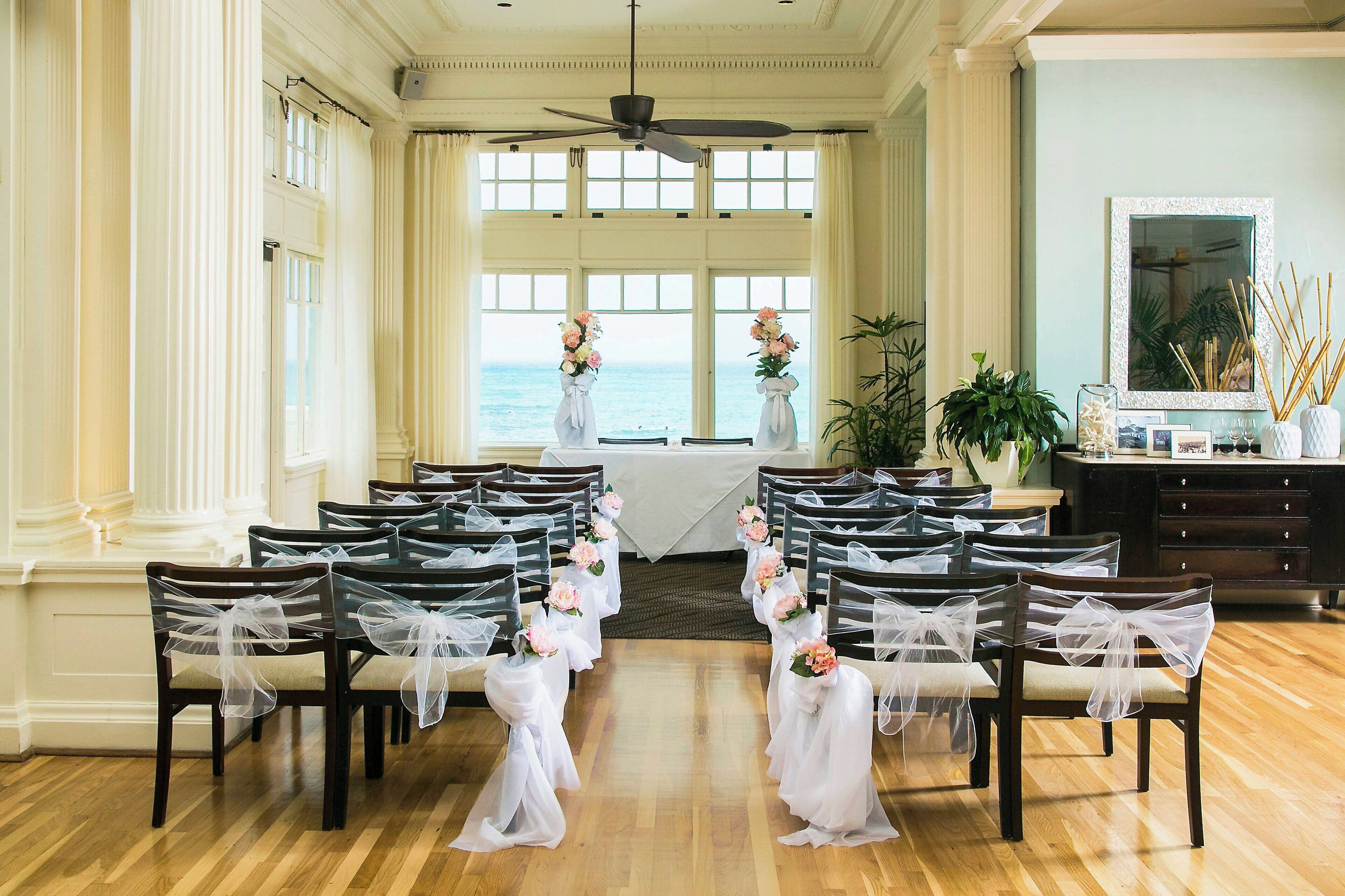 A wedding ceremony setup with rows of chairs, floral decorations, and a view of the ocean.