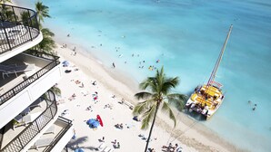 Ein Strand mit einem Boot, Palmen und Menschen.