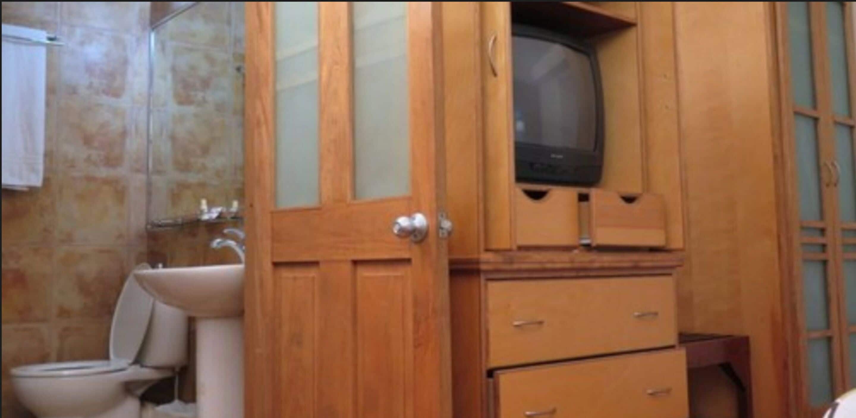 Un baño con un mueble de madera, un inodoro y un lavabo.