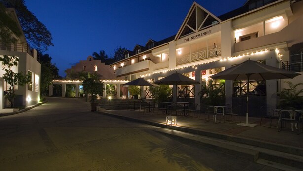 A hotel with outdoor seating and a sign reading "The Normandie". - The Normandie Hotel (Port of Spain)