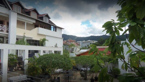 A multi-story building with balconies and outdoor seating areas. - The Normandie Hotel (Port of Spain)