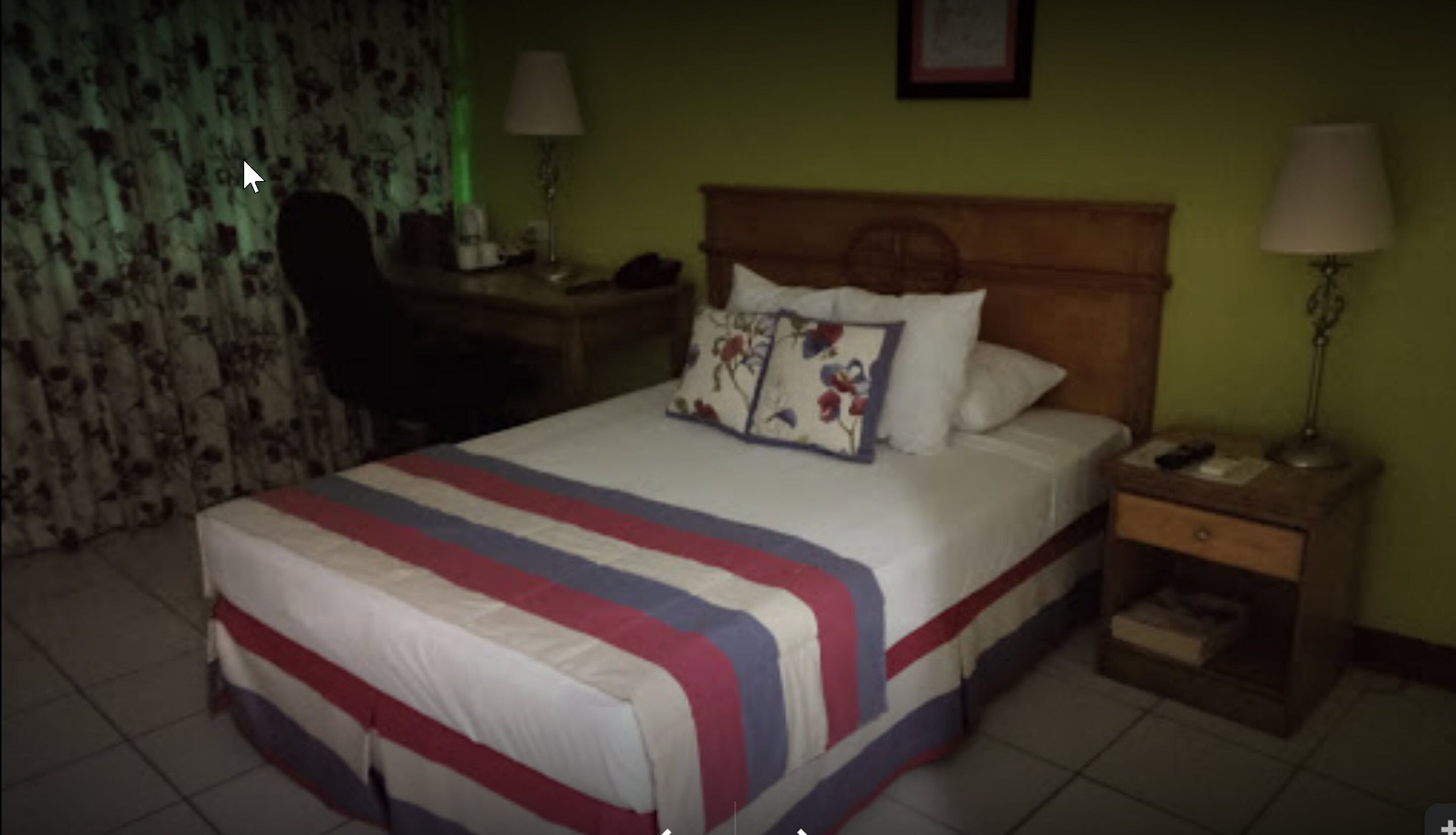 Una habitación de hotel con cama, escritorio, silla y mesita de noche.