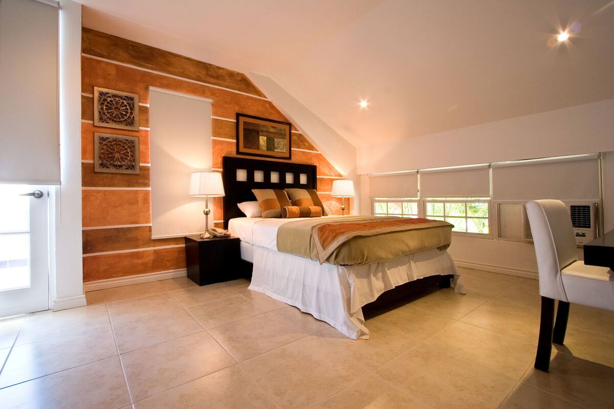 A bedroom with a bed, nightstands, a chair, and a window.