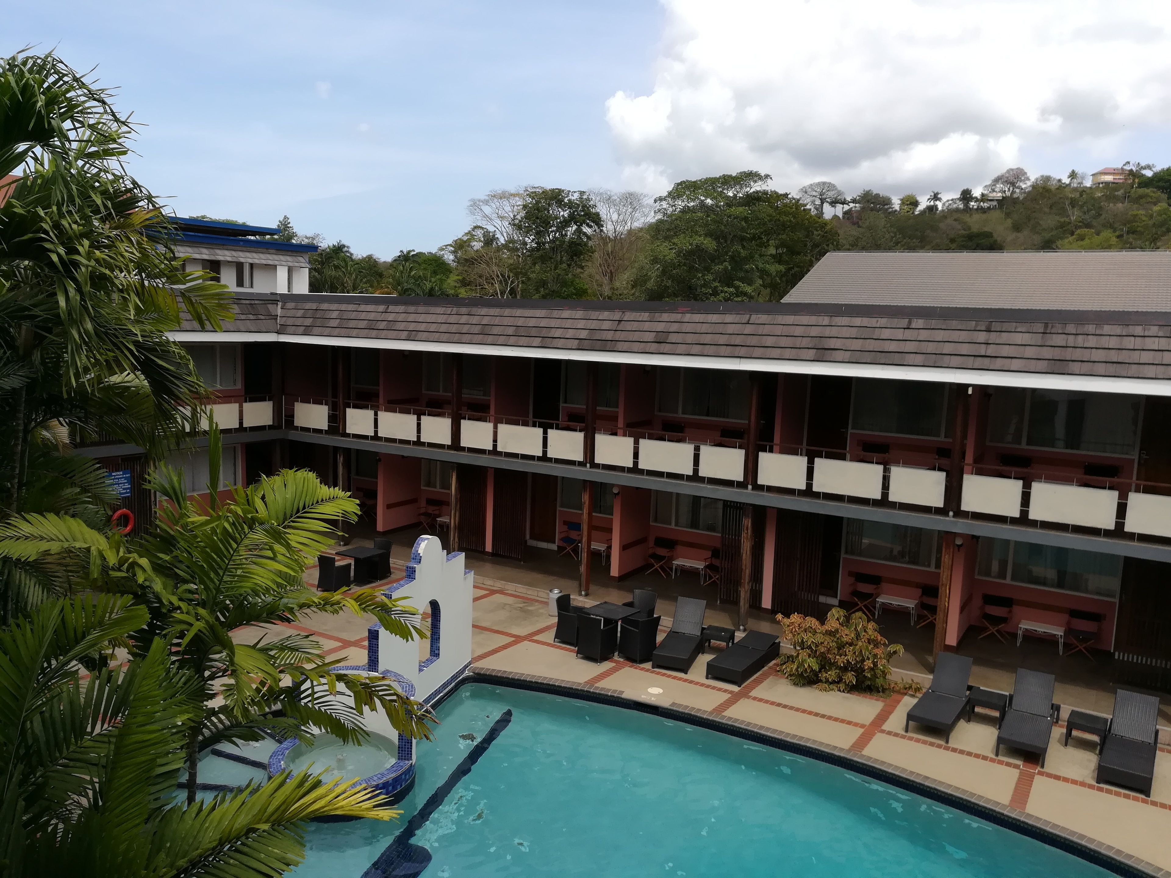 A hotel with a pool area, outdoor seating, and a view of the surrounding landscape.