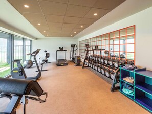 A gym with treadmills, elliptical machines, and a wall of dumbbells.