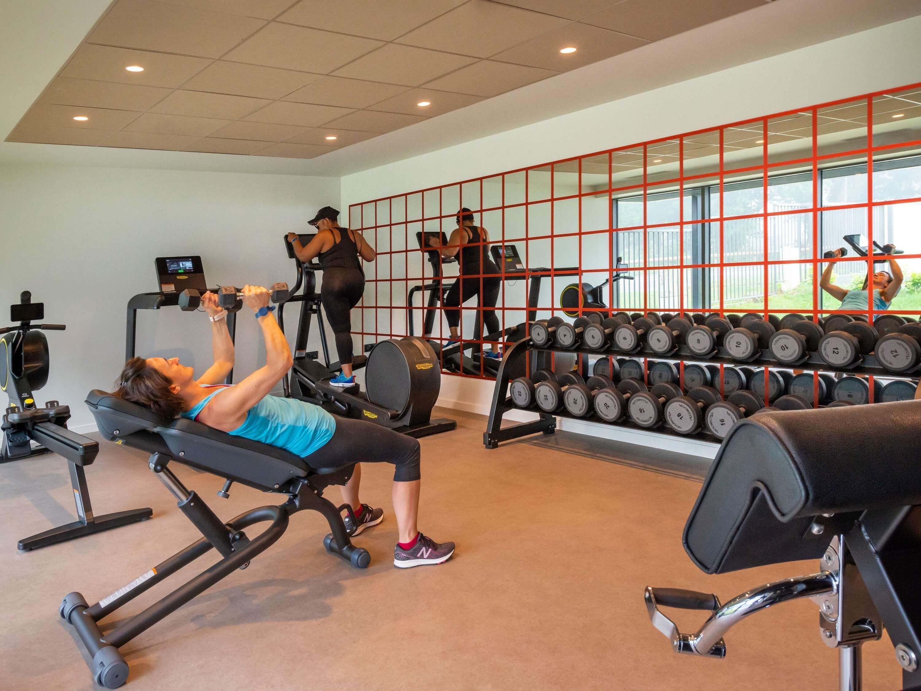 A gym with exercise equipment, a weight rack, and a large window.