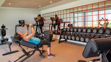 A gym with exercise equipment, a weight rack, and a large window.