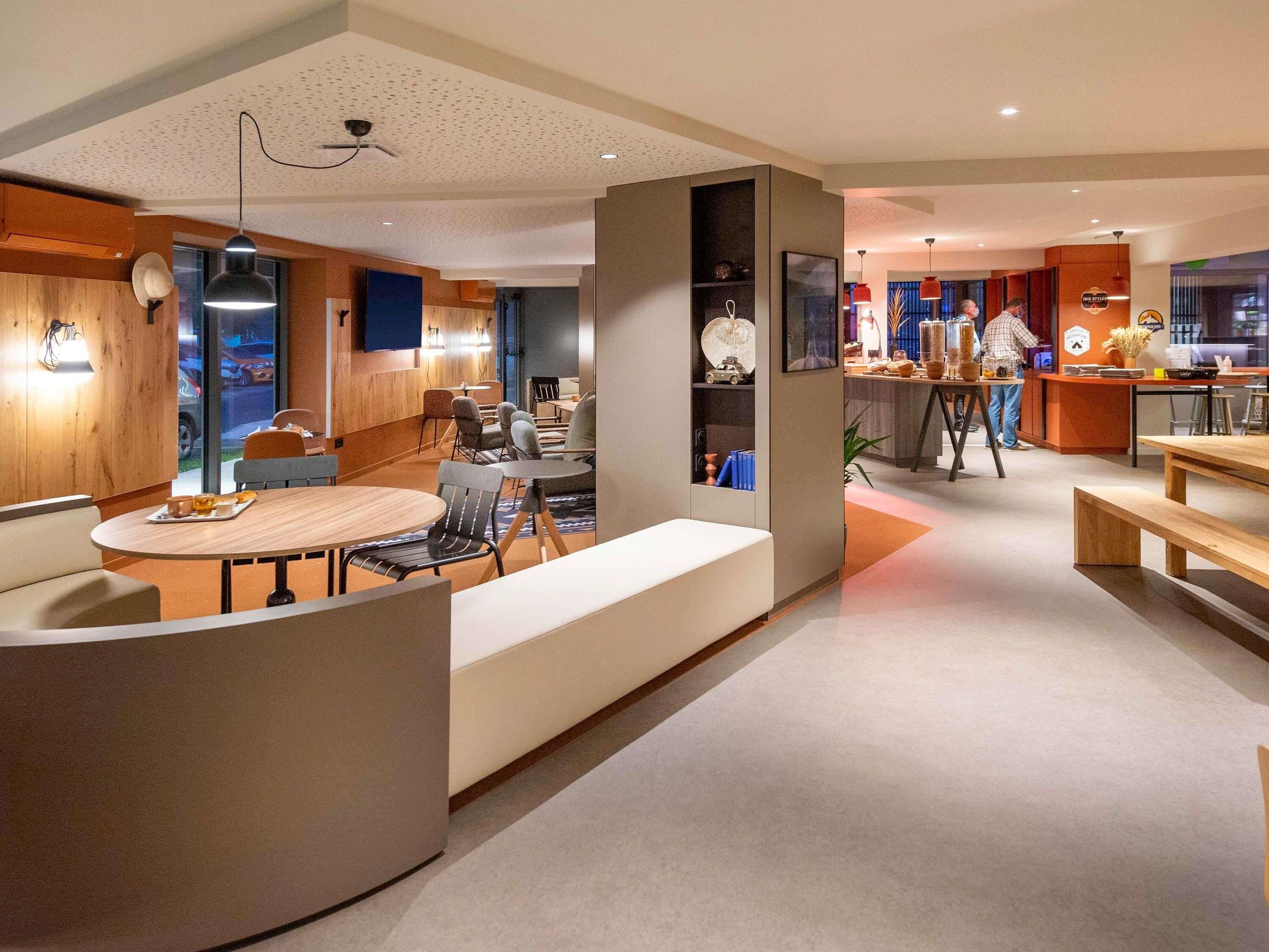 A modern hotel lobby with a seating area, a reception desk, and a bar/lounge area.