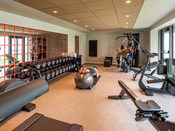 A gym with various exercise equipment, including dumbbells, a stationary bike, and a rowing machine. - Ibis Styles Rouen Parc Expo Zenith (Saint-Etienne-du-Rouvray)
