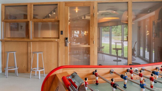 Una mesa de fútbolín en una habitación con armarios de madera y taburetes.