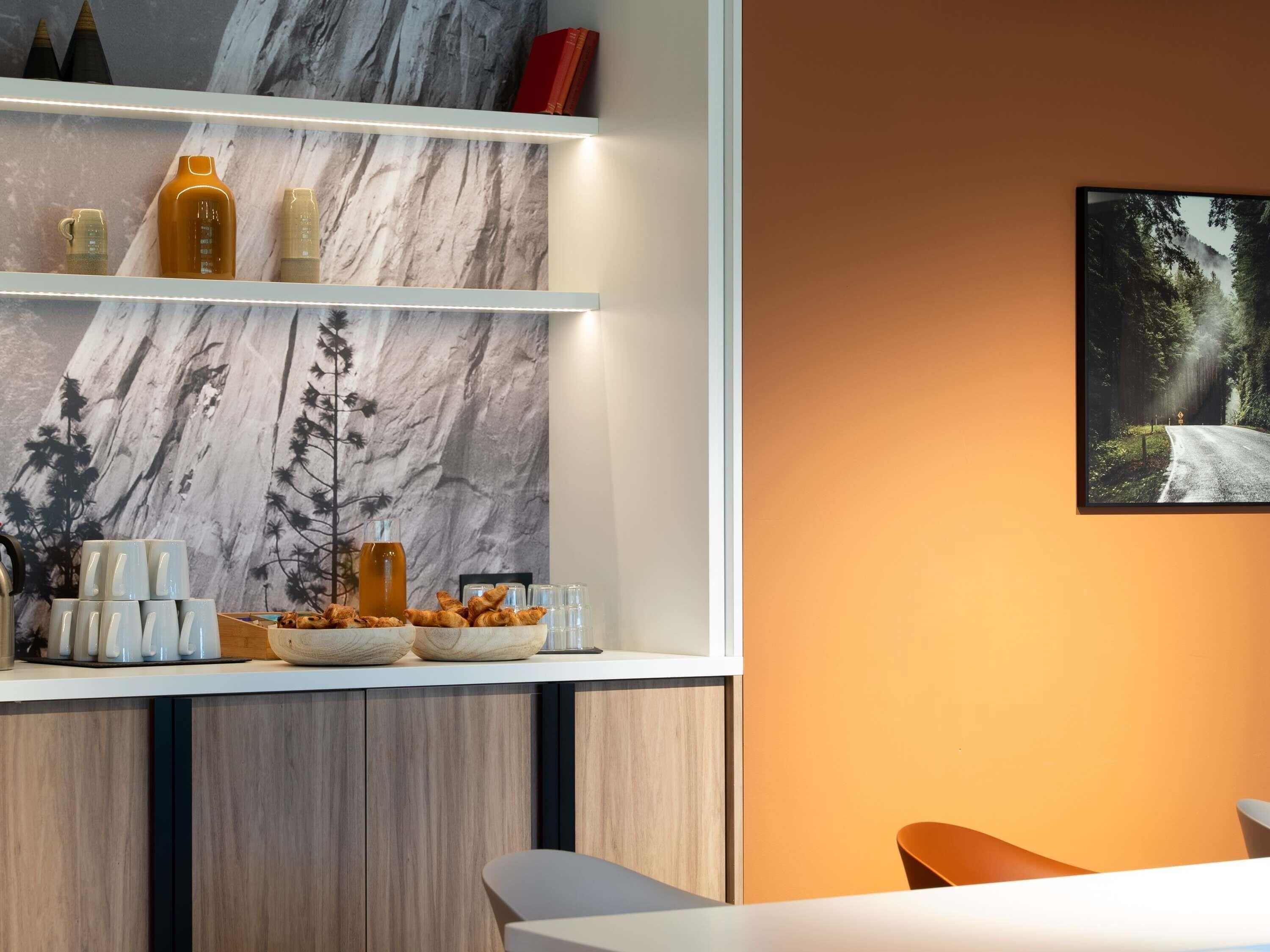 A modern kitchen with marble backsplash, wooden cabinets, and a dining area with a single chair.