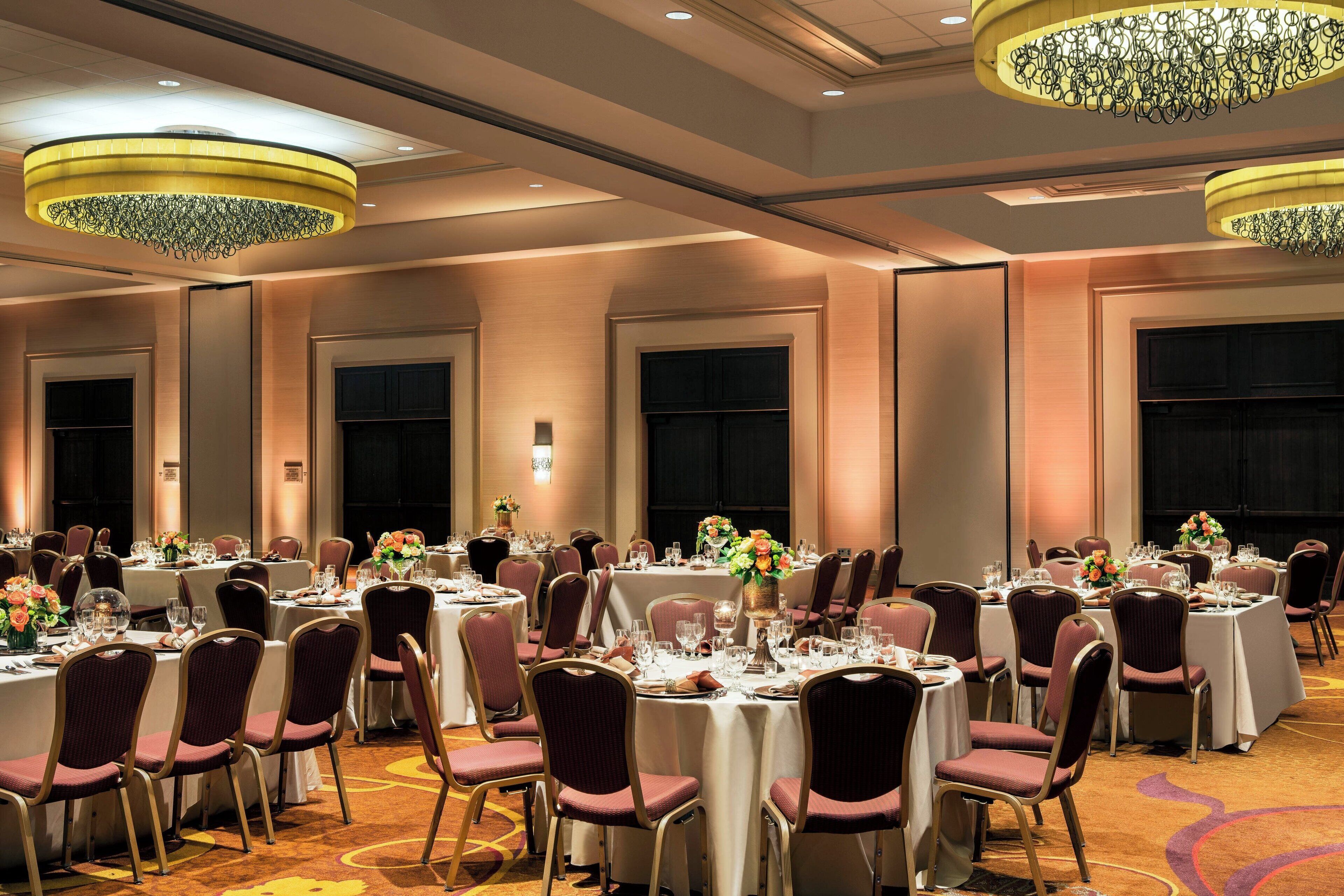 Un salón de banquetes con mesas redondas, sillas y candelabros.