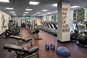 Une salle de sport équipée de tapis de course, d’appareils de musculation et d’un mur d’inspiration.