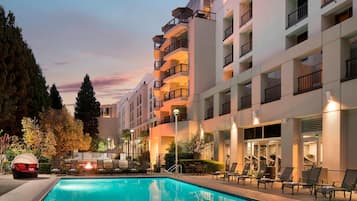 Una piscina al aire libre, camas de piscina con cargo, sombrillas