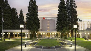 Un hotel Marriott con un patio central, rodeado de árboles altos y senderos bien iluminados.