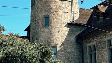 Ein Steinturm mit einem kegelförmigen Dach und einer Turmspitze, umgeben von Stromleitungen.