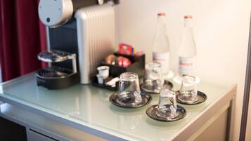 Eine Küchenarbeitsplatte mit einer Kaffeemaschine, zwei Wasserflaschen und einer Ablage mit Tassen und einer kleinen Schale.