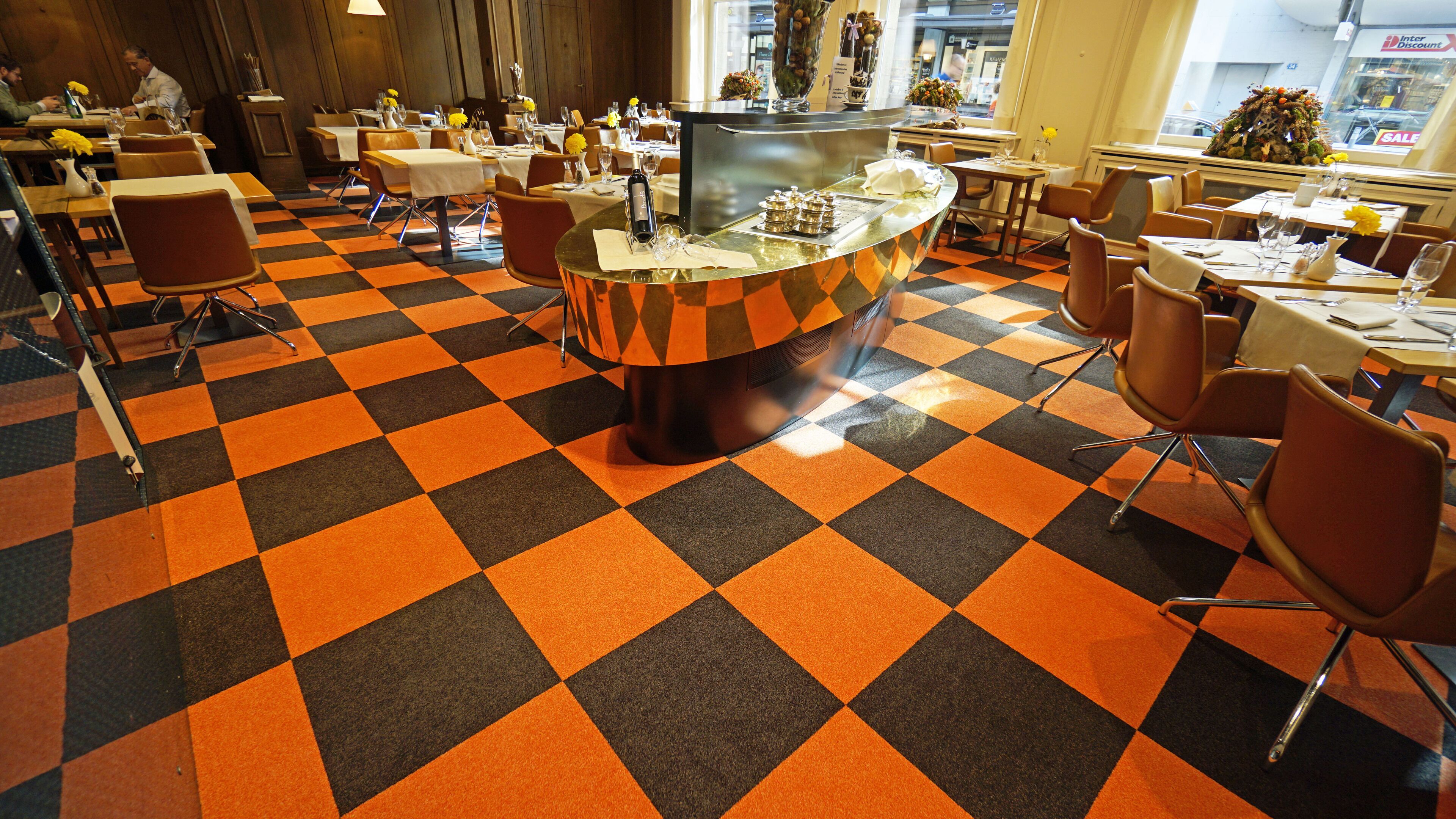 A restaurant with a checkered floor pattern and multiple dining tables.