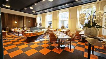A hotel dining area with a checkered floor, multiple tables, and chairs.