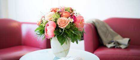Una mesa de vidrio con un florero y una revista.