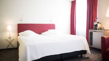 Une chambre d’hôtel avec un lit, un bureau, une chaise et une lampe.