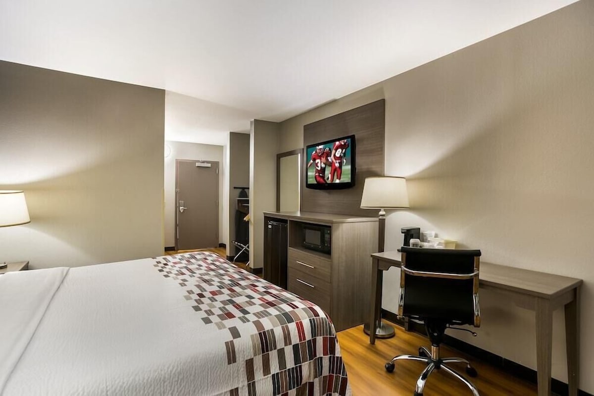 A hotel room with a bed, a desk, a television, and a chair.