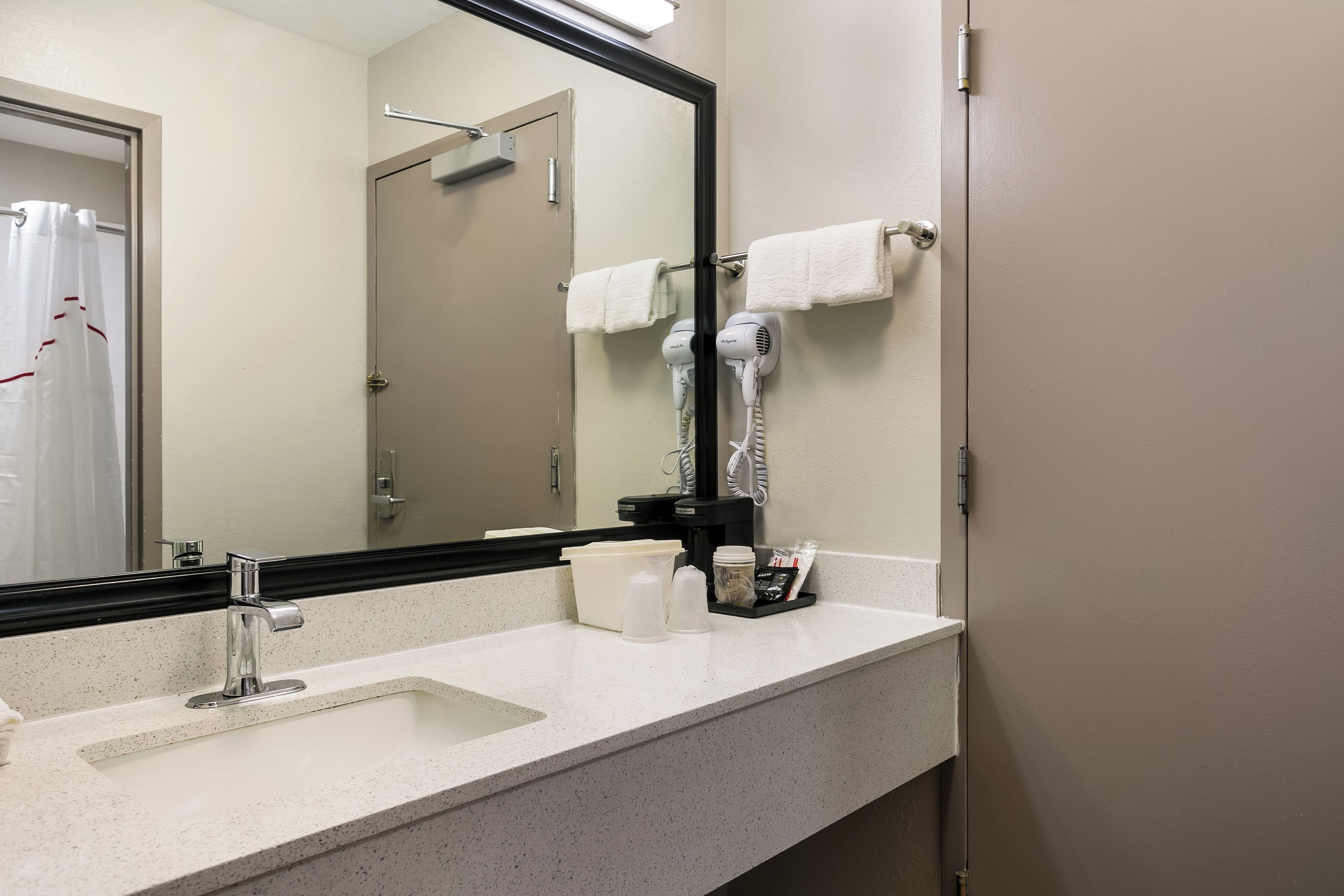 A bathroom with a sink, a mirror, a hairdryer, and a towel rack.