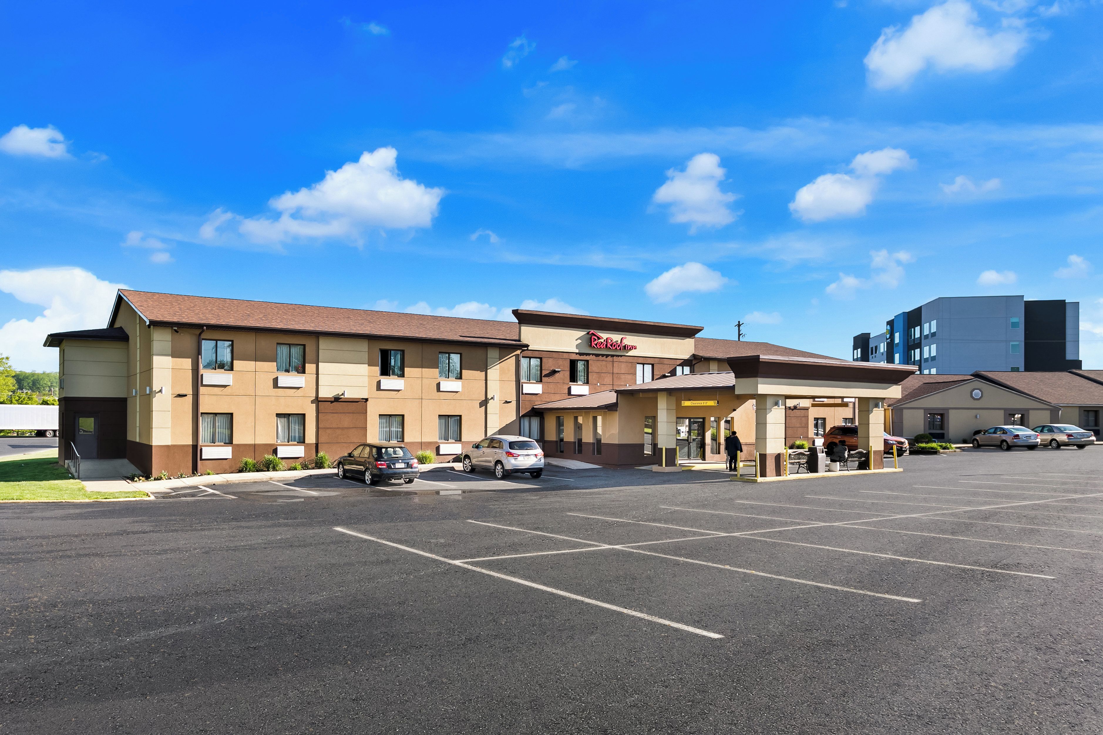 A Red Roof Inn with a parking lot and a clear blue sky.