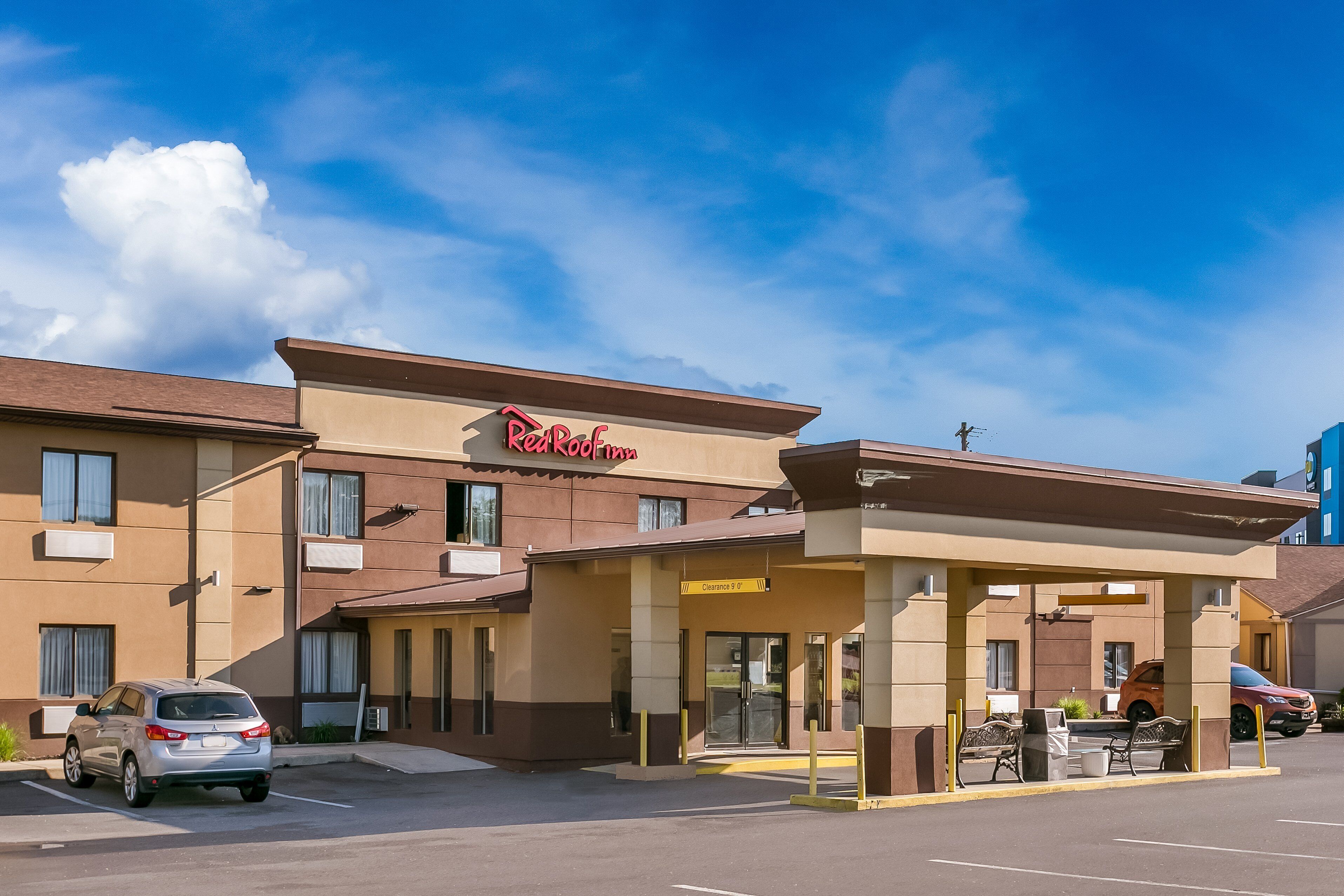 A Red Roof Inn with a clear sky, parking area, and a covered entrance.