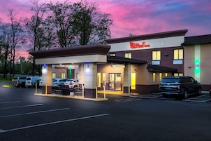 Un hotel Red Roof Inn con estacionamiento, acceso para vehículos y entrada al edificio.