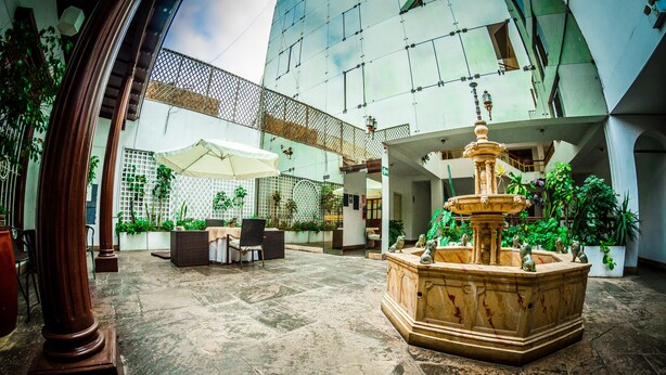 Une cour spacieuse avec une fontaine centrale, entourée de plantes en pot et de mobilier d’extérieur.