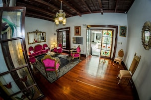 Un salón amplio con suelo de madera, una araña y un espejo grande.