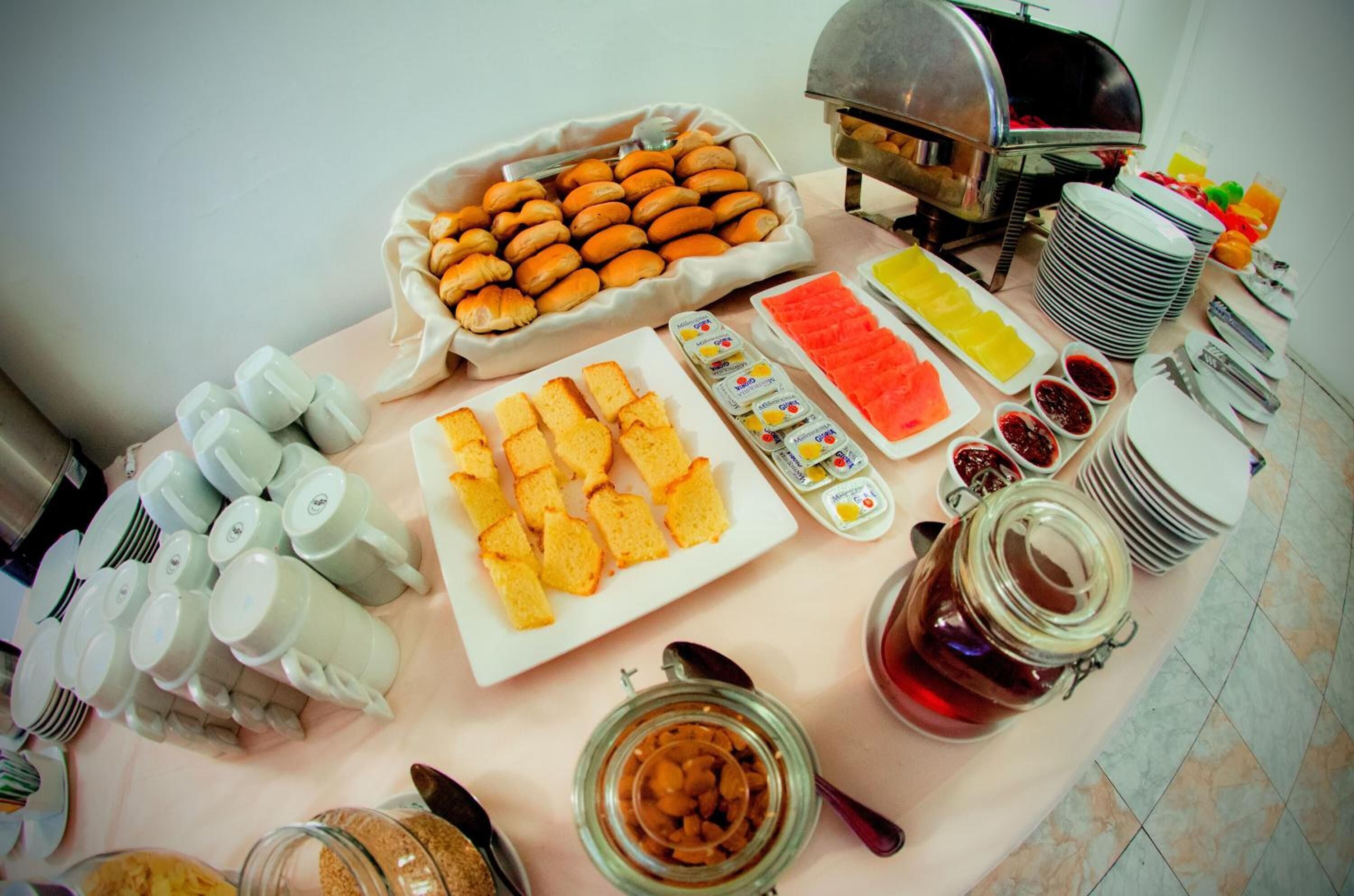 Uma mesa de buffet com diversos alimentos, incluindo doces, pão e acompanhamentos.