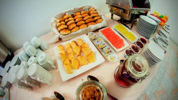 Uma mesa de buffet com diversos alimentos, incluindo doces, pão e acompanhamentos.