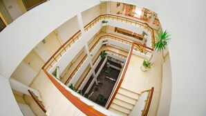Un atrium à plusieurs niveaux, doté d’un espace central ouvert, de rampes et de plantes en pot.
