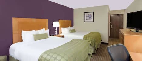 A hotel room with two beds, a desk, a chair, a television, and a door.