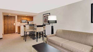 A modern living room with a beige sofa, a black coffee table, and a dining area with a table and chairs.