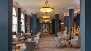 A spacious lobby with a central staircase, multiple seating areas, and a grand chandelier. - Belton Woods Hotel, Spa & Golf Resort (Grantham)