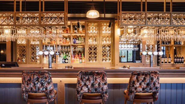 A bar area with three stools, a bar counter, and shelves stocked with bottles and glasses. - Belton Woods Hotel, Spa & Golf Resort (Grantham)