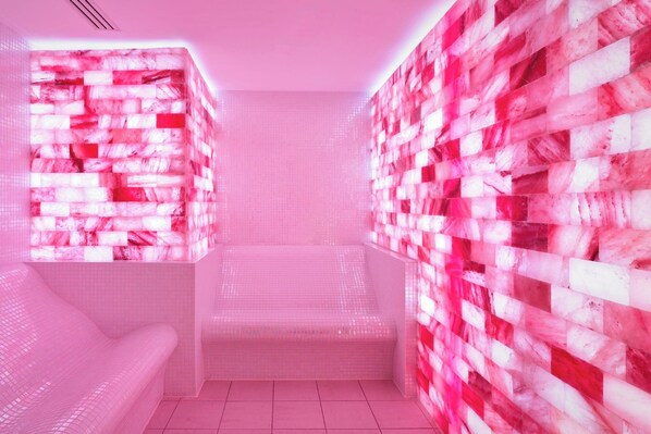 Una habitación con pared de diseño rosa y blanco, un sofá blanco y suelo de baldosas.